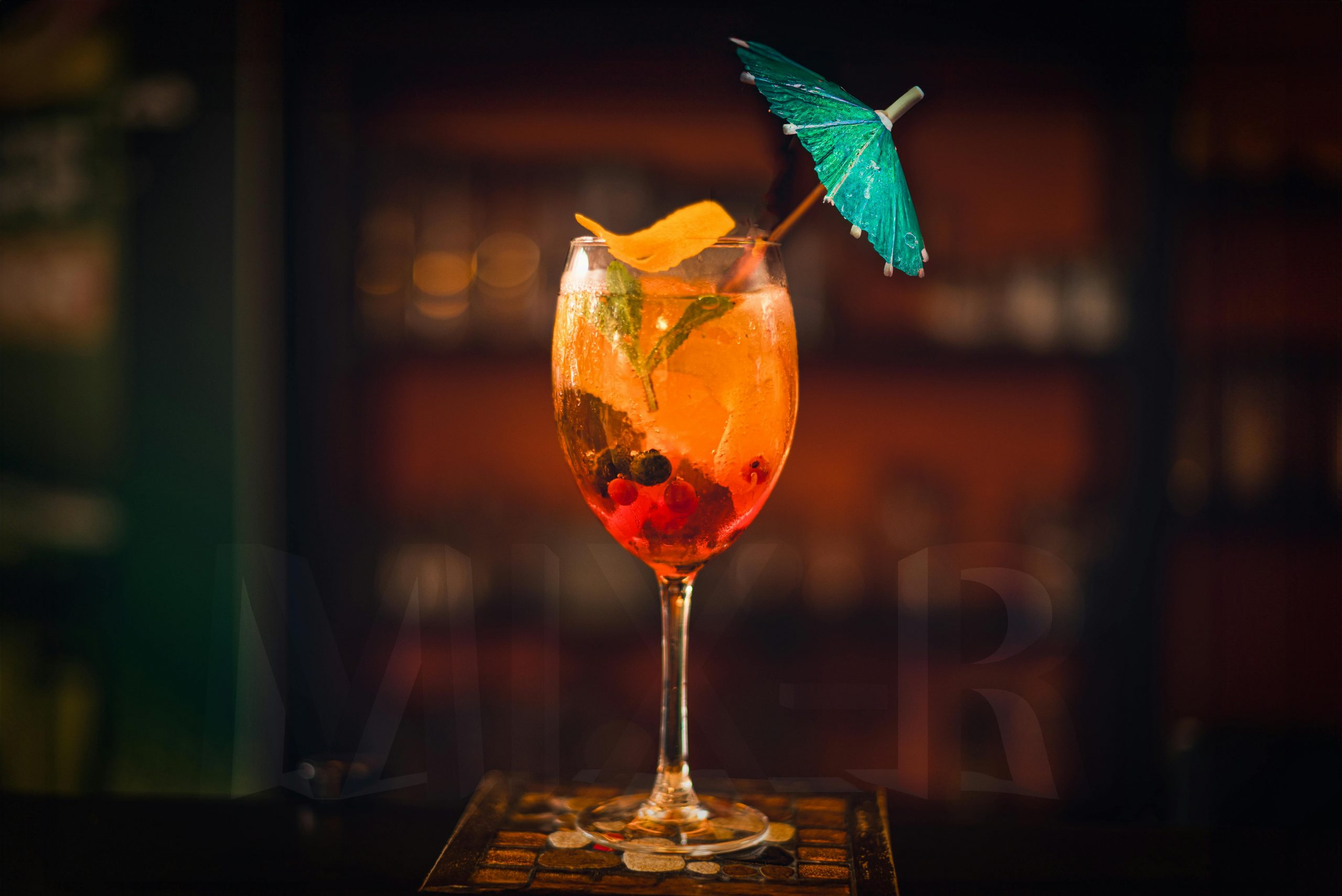 Colorful cocktail in a glass with a blue umbrella, perfect for summer vibes.